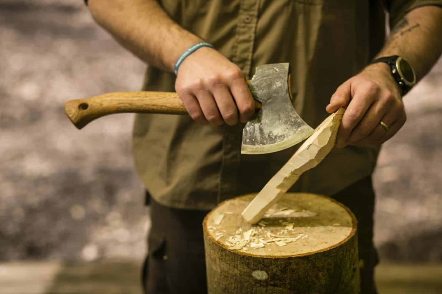 a person using an axe to cave some wood during a bushcraft course in brittany