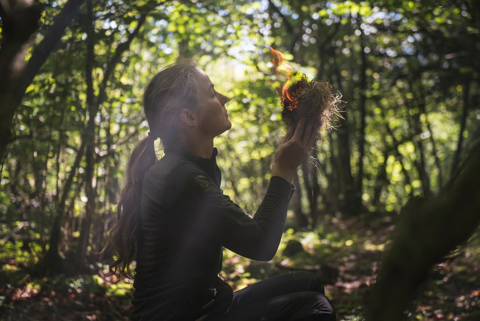 Woman making fire primitive technique, outdoor training survival course crozon brittany 